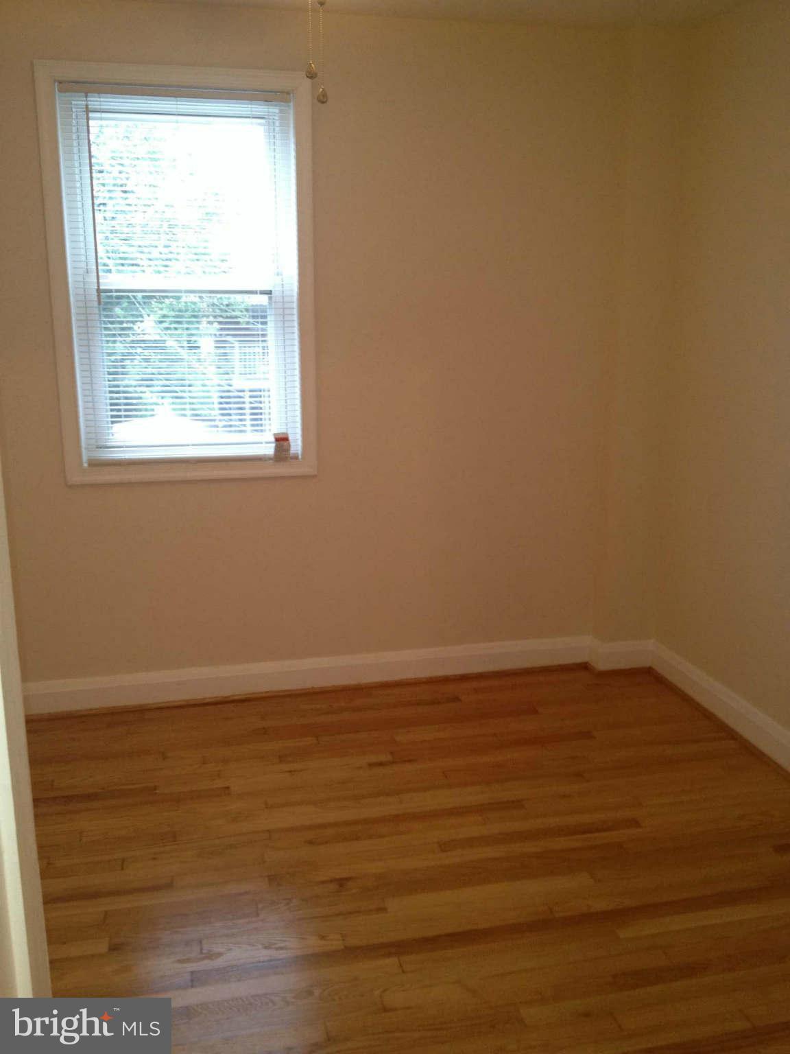 907 Masefield Road Baltimore, MD 21207 - Photo 12 of 23 an empty room with wooden floor and windows