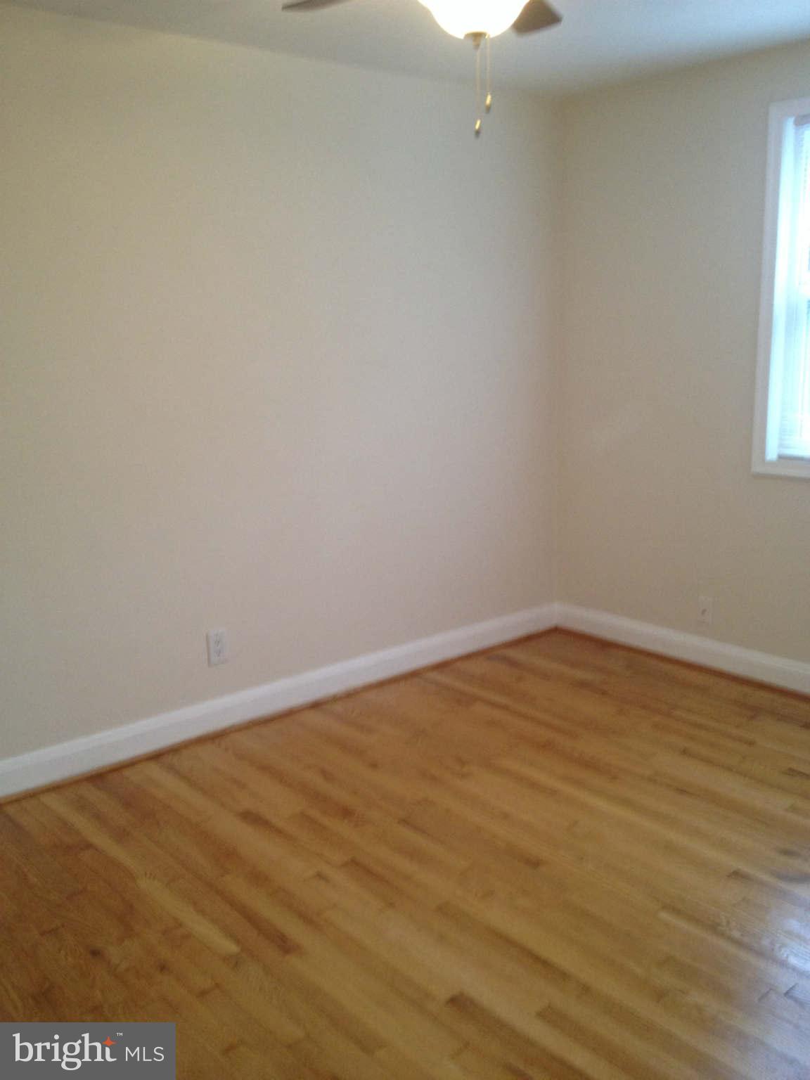 907 Masefield Road Baltimore, MD 21207 - Photo 13 of 23 a view of an empty room with wooden floor and a window