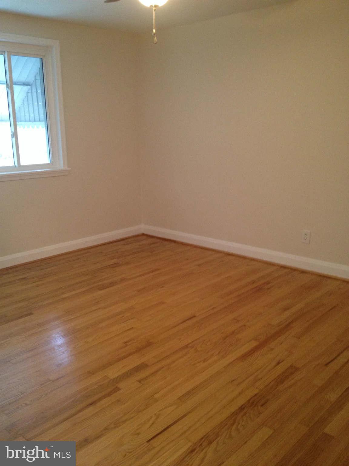 907 Masefield Road Baltimore, MD 21207 - Photo 14 of 23 a view of an empty room with wooden floor and a window