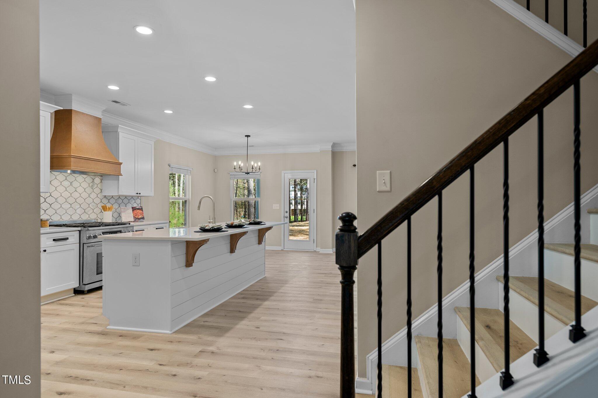 2009 Delphi Way Wake Forest, NC 27587 - Photo 7 of 40 a large white kitchen with kitchen island a stove a sink wooden floor and cabinets