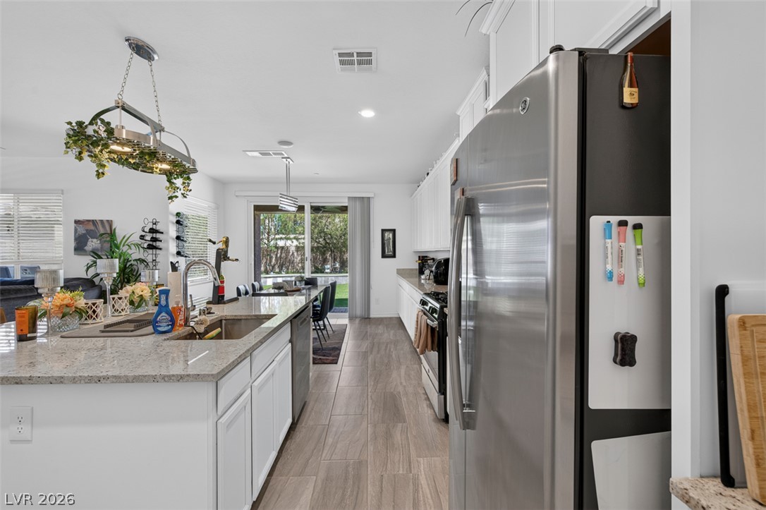 1824 Redland Ridge Street Henderson, NV 89002 - Photo 10 of 69 An open-concept kitchen features a large island, stainless steel appliances, and outdoor access.