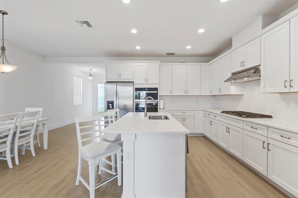 44319 Panther Drive Punta Gorda, FL 33982 - Photo 10 of 49 a kitchen with stainless steel appliances granite countertop a stove top oven a sink refrigerator and white cabinets with wooden floor