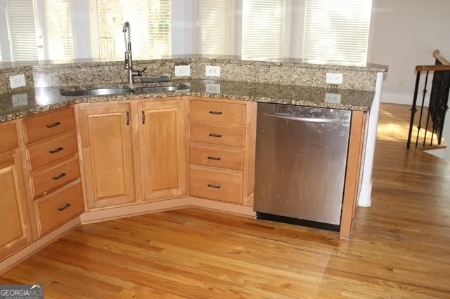 a kitchen with stainless steel appliances granite countertop a sink window and cabinets
