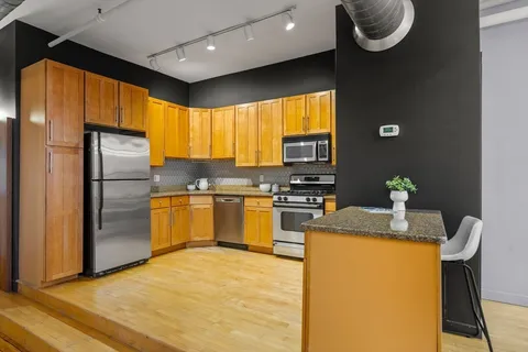 a kitchen with granite countertop a refrigerator a sink dishwasher with a dining table and chairs