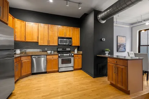 a kitchen with stainless steel appliances granite countertop a stove a sink and a refrigerator