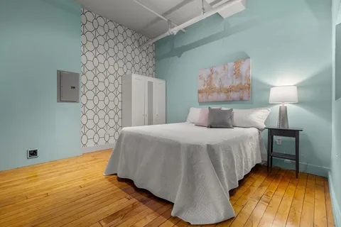 a bedroom with a bed and a wooden floor