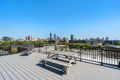 a view of a rooftop deck with chairs and wooden floor