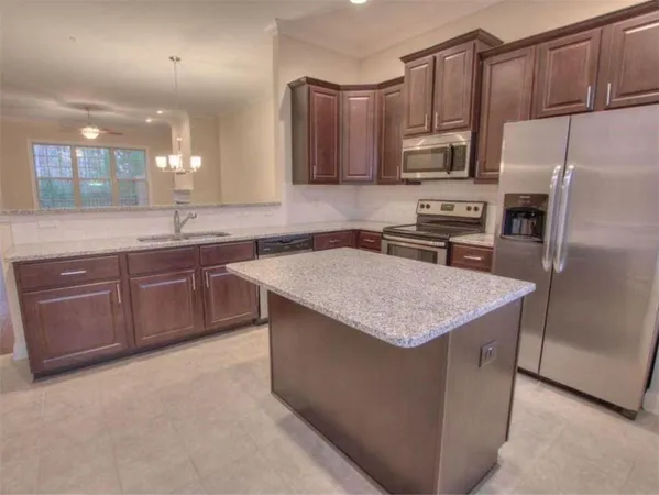a kitchen with stainless steel appliances a sink a stove a refrigerator a center island and cabinets