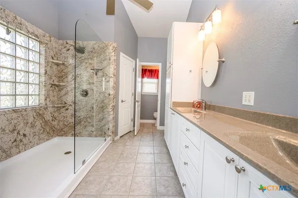 a spacious bathroom with a granite countertop sink a mirror and a bathtub