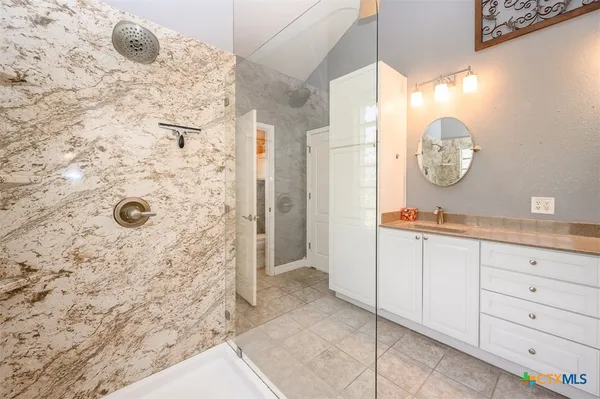 a bathroom with a granite countertop sink a mirror and shower