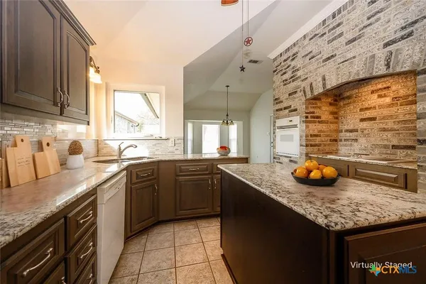 a kitchen with granite countertop kitchen island stainless steel appliances a sink window and cabinets