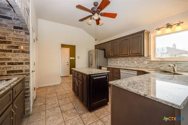 a kitchen with stainless steel appliances granite countertop a stove a sink and a microwave