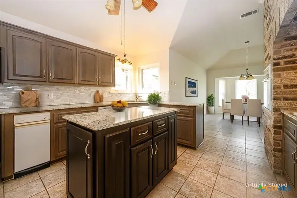 a kitchen with stainless steel appliances granite countertop a sink counter space and a view of living room