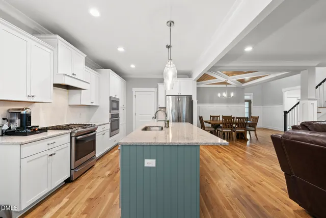 a kitchen with stainless steel appliances granite countertop a sink dishwasher a stove a dining table and chairs with wooden floor