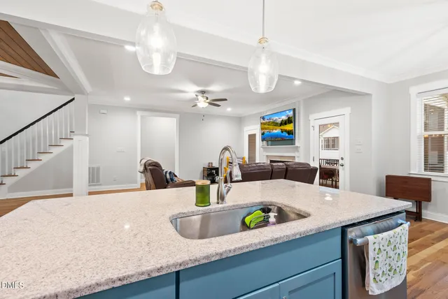 a kitchen with kitchen island granite countertop a sink a counter top space and living room view