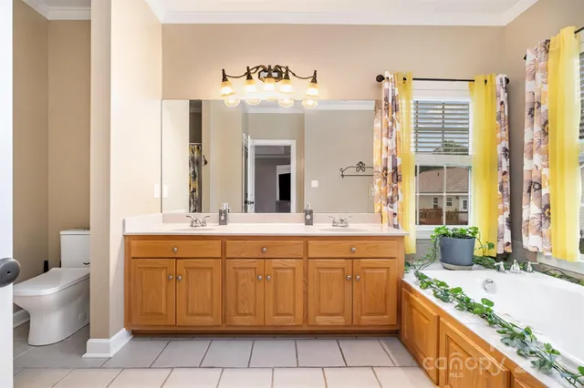 a spacious bathroom with a granite countertop double vanity sink mirror bathtub and toilet