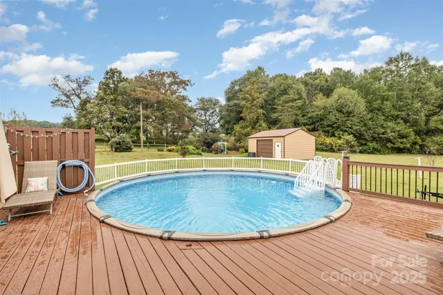 a view of a swimming pool with a patio and wooden fence