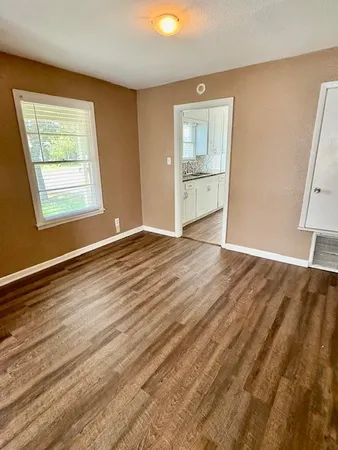 a view of an empty room with a window and wooden floor