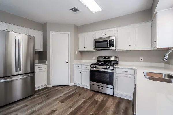 an empty room with wooden floor fan and windows
