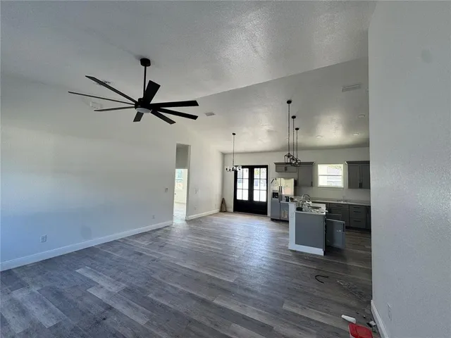 an empty room with wooden floor a ceiling fan and windows