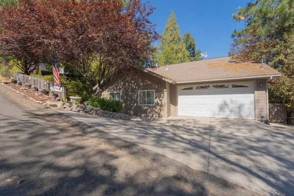 a view of a house with a yard and large tree