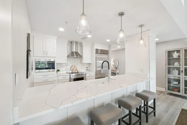 a kitchen with kitchen island a white counter top space a sink stainless steel appliances and cabinets
