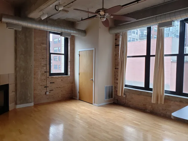 an empty room with windows chandelier fan and windows
