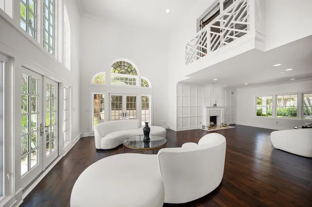 a large white kitchen with a large counter top space a sink stainless steel appliances and cabinets