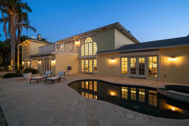 a view of a porch with couches plants and large trees