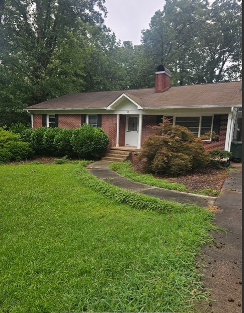 A charming brick home welcomes with a winding walkway and mature landscaping, offering inviting curb appeal.