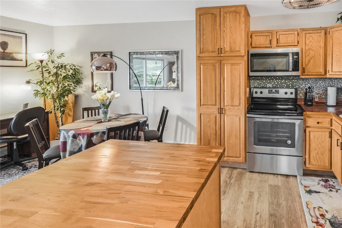 150 Evergreen Road, Unit C303 Dillon, CO 80435 - Photo 12 of 35 a kitchen with stainless steel appliances kitchen island granite countertop a refrigerator a stove top oven and a dining table with wooden floor
