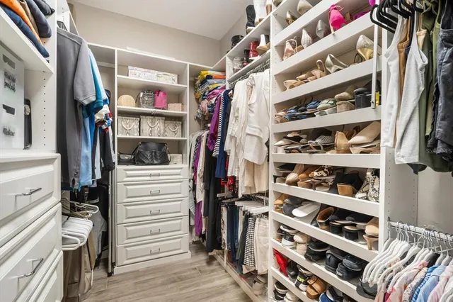 a view of walk in closet with clothes and shoes