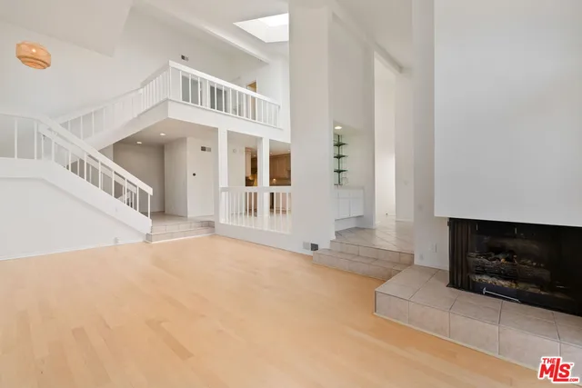 a view of an empty room with wooden floor and a fireplace