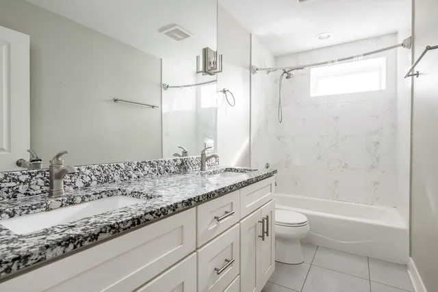 a bathroom with a granite countertop sink a toilet and bathtub