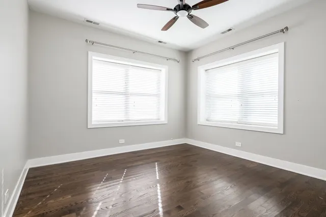 a view of a room with wooden floor fan and windows