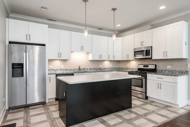 a kitchen with stainless steel appliances granite countertop a stove a refrigerator a sink and white cabinets