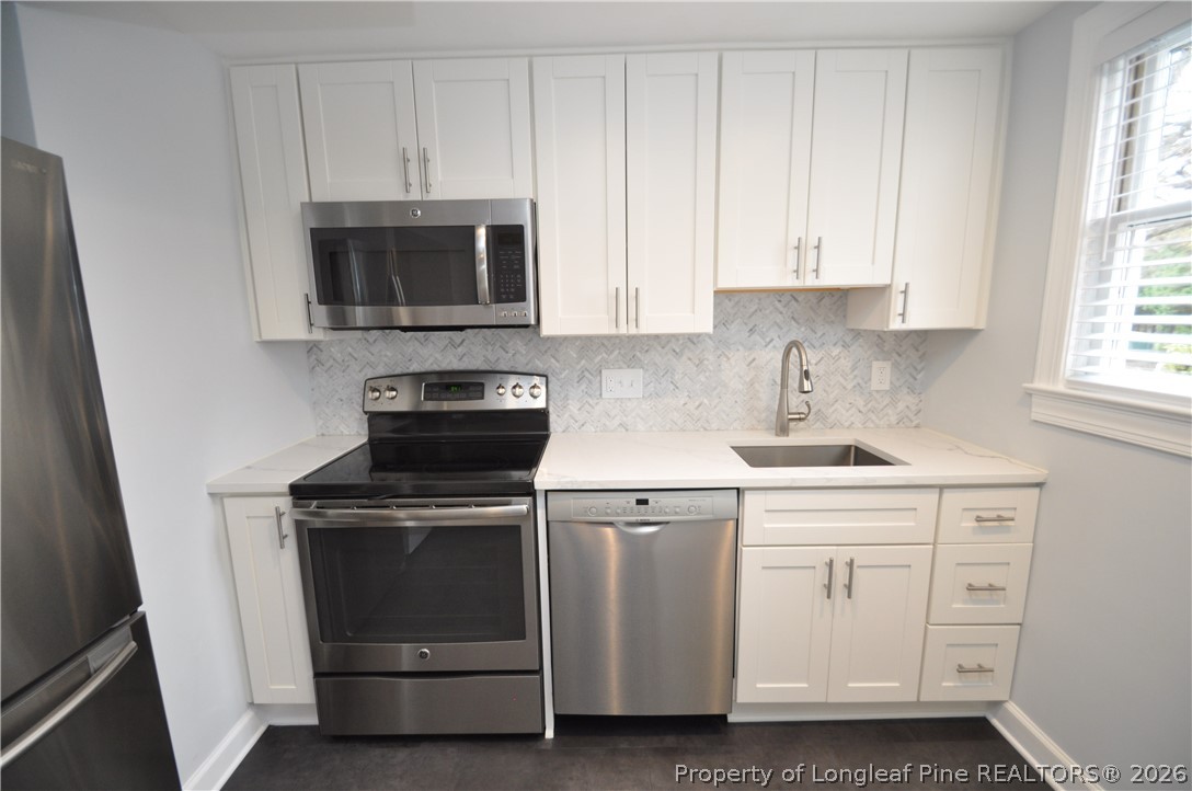 1008 Nichols Drive Raleigh, NC 27605 - Photo 18 of 33 a kitchen with white cabinets and stainless steel appliances