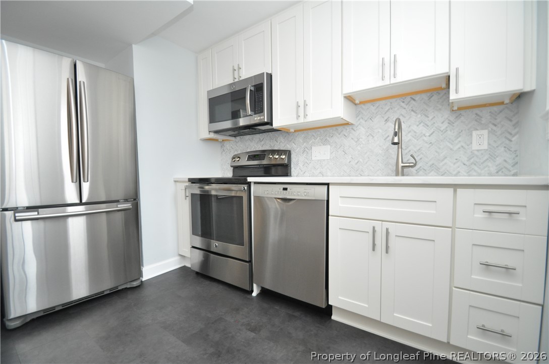 1008 Nichols Drive Raleigh, NC 27605 - Photo 21 of 33 a kitchen with white cabinets and stainless steel appliances