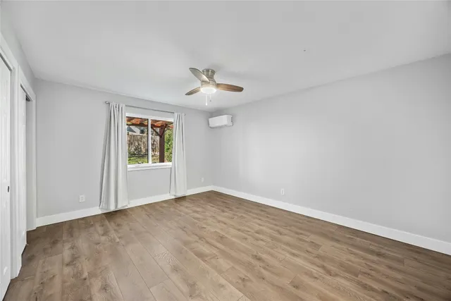 a view of an empty room with wooden floor and a ceiling fan