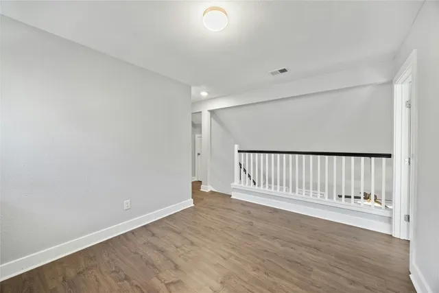 an empty room with wooden floor ceiling fan and windows
