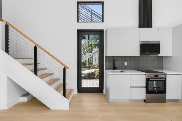 a kitchen with a refrigerator a stove top oven and a potted plant