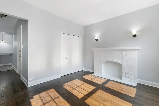 a view of a livingroom with wooden floor and a fireplace