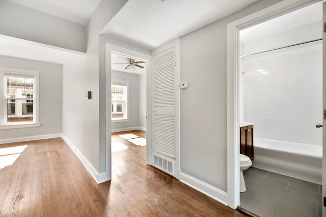 a view of a hallway with wooden floor and a bathroom