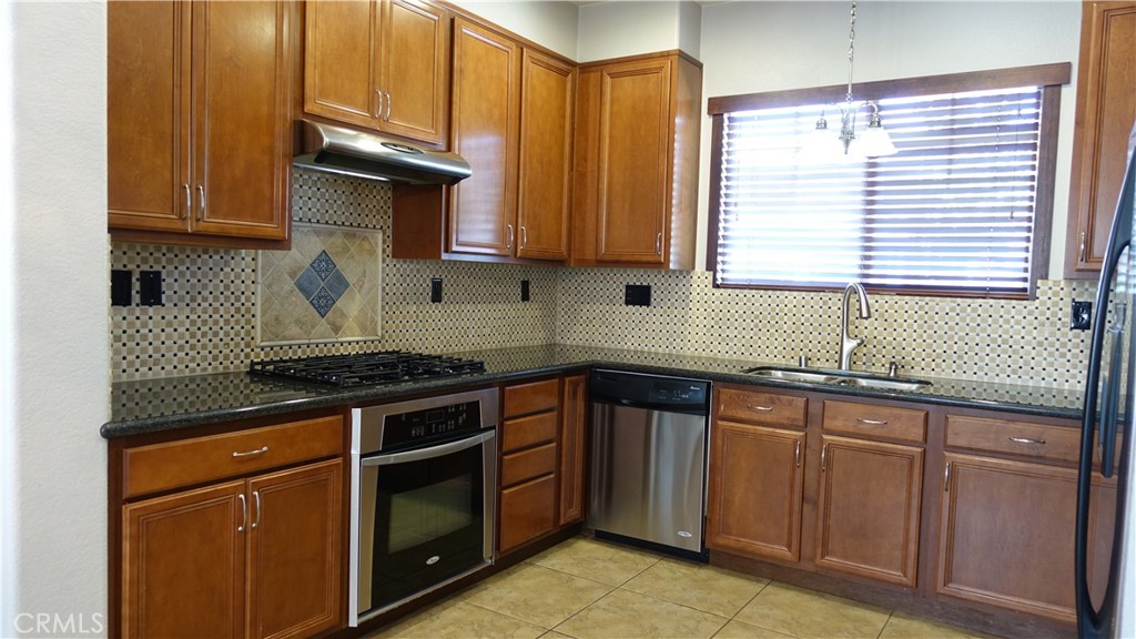 33953 Lily Road Yucaipa, CA 92399 - Photo 4 of 38 a kitchen with granite countertop wooden cabinets stainless steel appliances and a sink