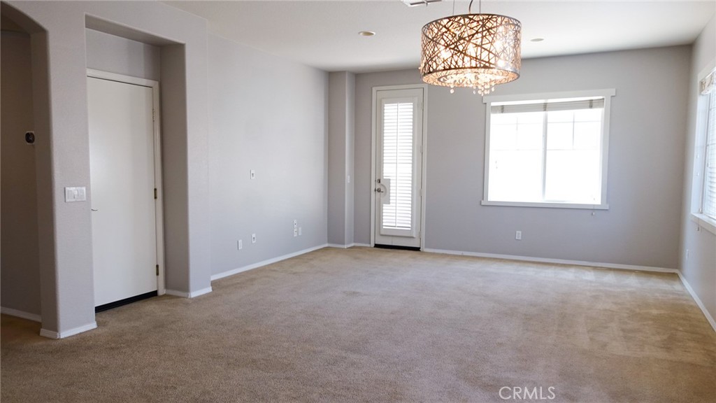 33953 Lily Road Yucaipa, CA 92399 - Photo 6 of 38 an empty room with a chandelier fan and windows