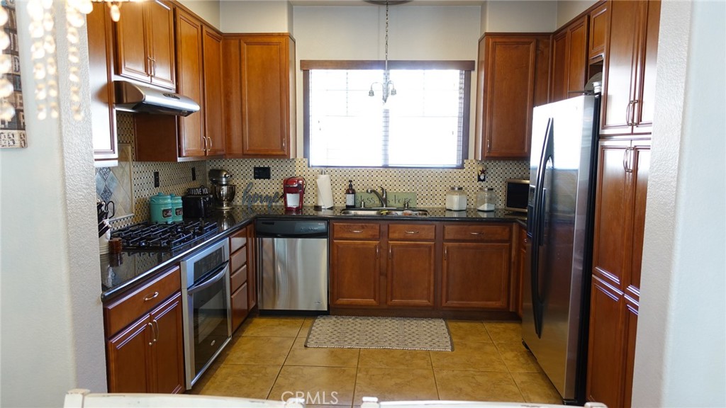 33953 Lily Road Yucaipa, CA 92399 - Photo 10 of 38 a kitchen with stainless steel appliances granite countertop a refrigerator a sink a stove a microwave and wooden cabinets