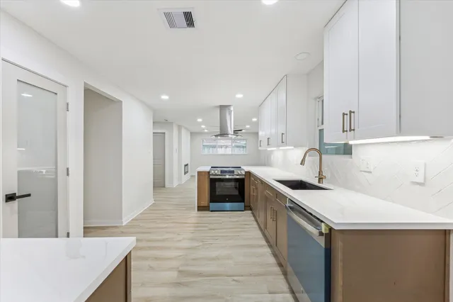 a large kitchen with stainless steel appliances granite countertop a stove top oven a sink and dishwasher