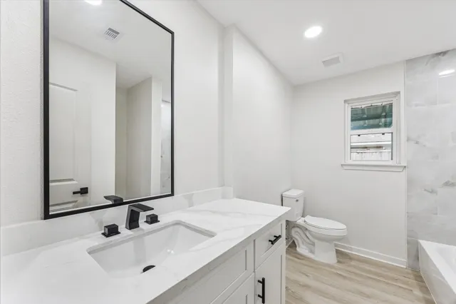a bathroom with a granite countertop sink toilet and mirror
