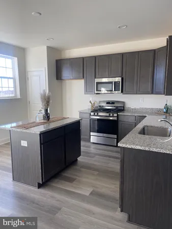 a kitchen with stainless steel appliances granite countertop a stove a sink dishwasher and a refrigerator with wooden floor