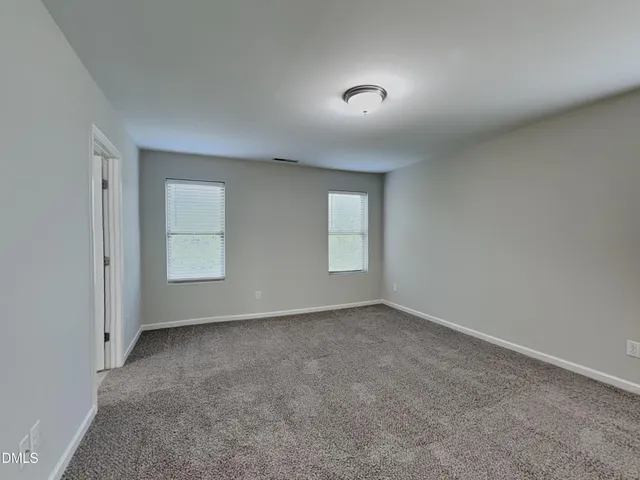 a view of an empty room with window and closet area